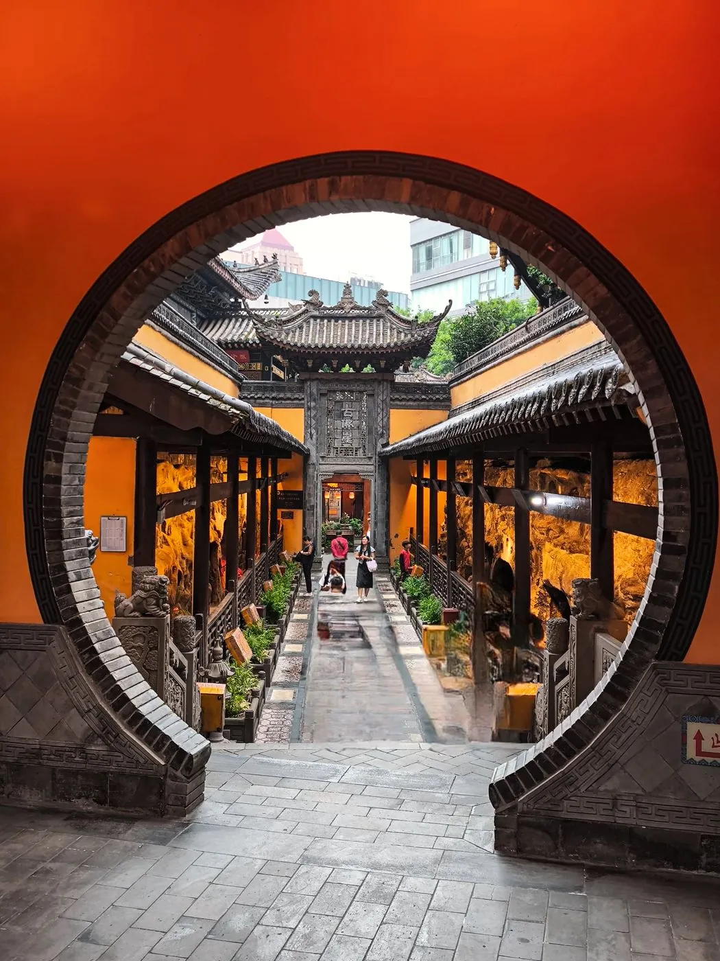 Porte ronde rouge ouvrant sur la cour d’un temple chinois