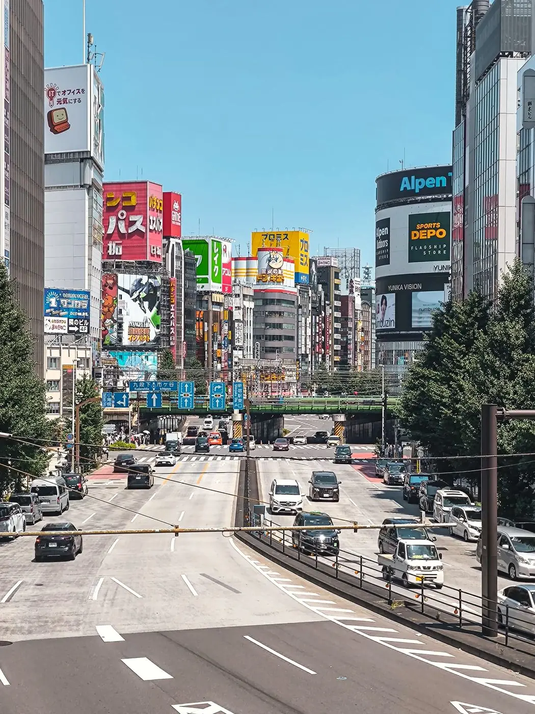 Grande avenue de Shinjuku bordée d’enseignes colorées sous un ciel bleu