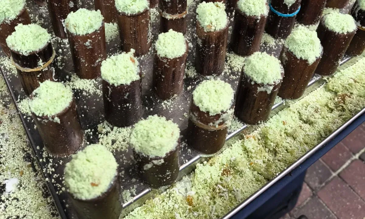 Putu bambu, gâteaux de riz à la pandan cuits dans le bambou et couverts de noix de coco, spécialité de rue malaisienne
